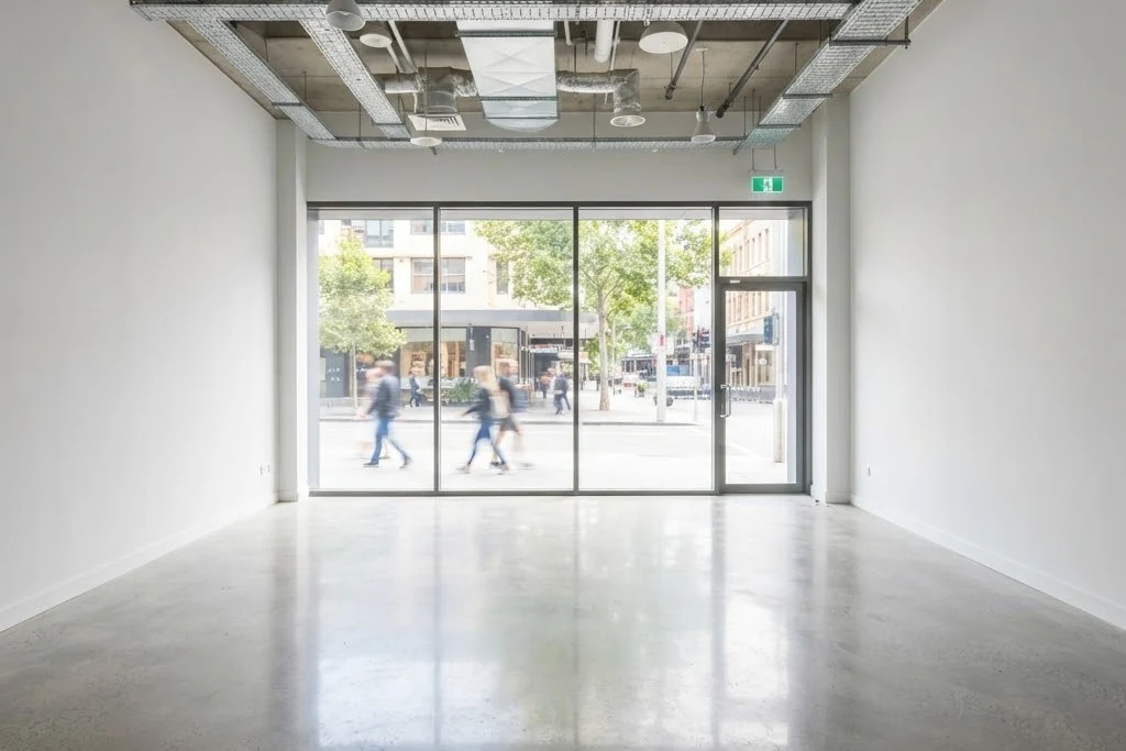 An empty retail unit with a polished concrete floor and a full width glazed shopfront onto the street, for retail and office in Brampton